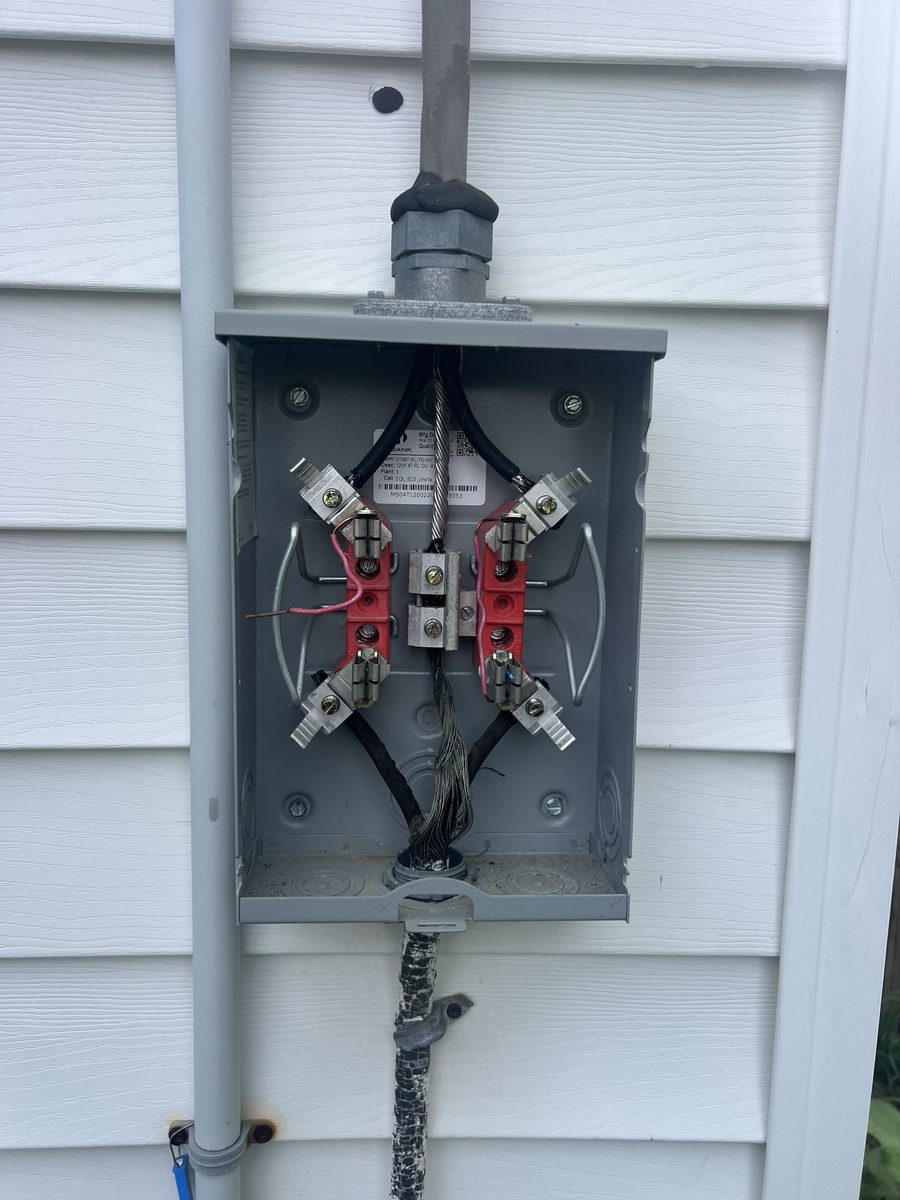 Before: old open meter base on vinyl siding with exposed connections and a weathered, cracked service cable